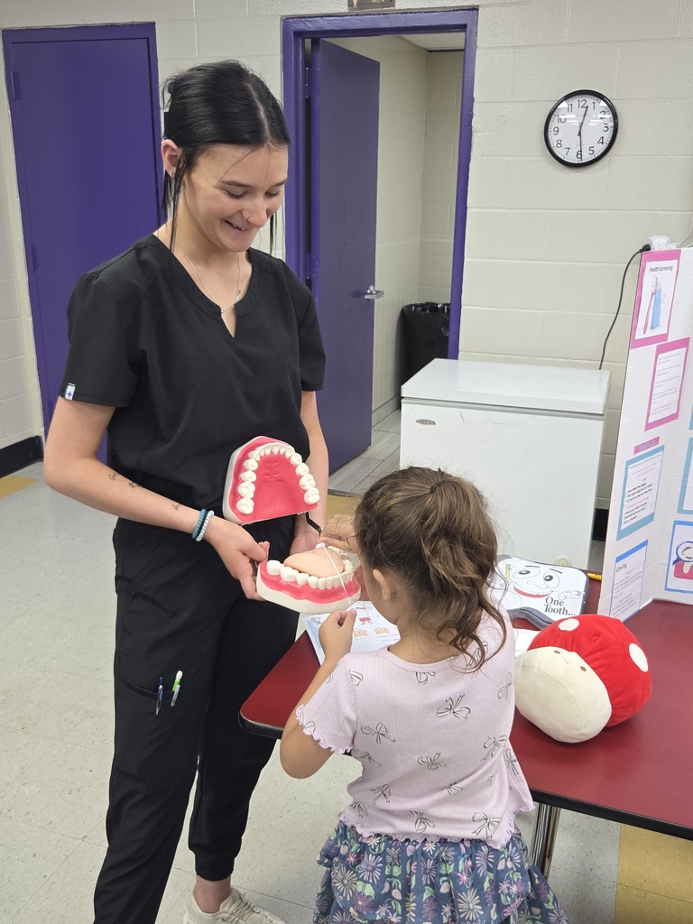 A Pre-K student is learning about healthy mouth care from a high school student.
