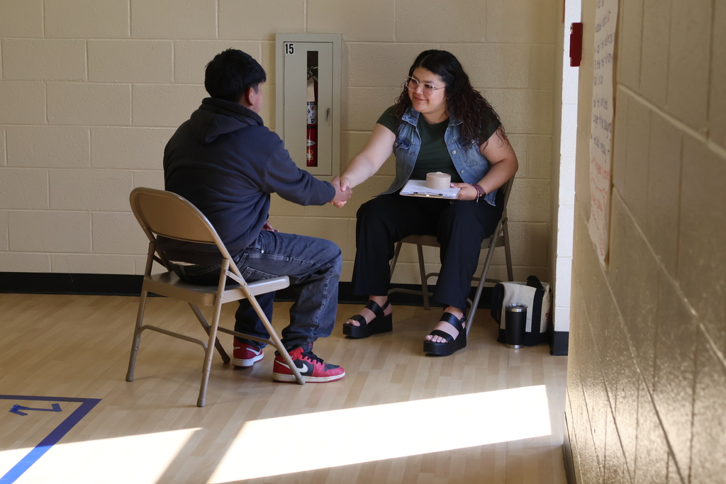 A student shakes a woman's hand at East Side Elementary School's Amazing Shake competition. 