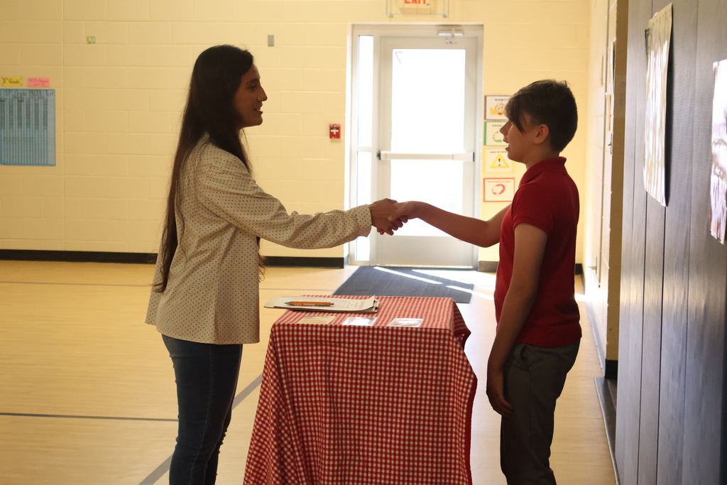 A student shakes a woman's hand at East Side Elementary School's Amazing Shake competition. 