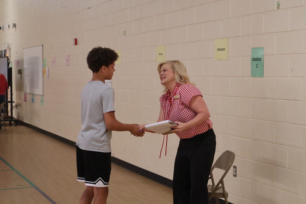 A student shakes a woman's hand at East Side Elementary School's Amazing Shake competition. 