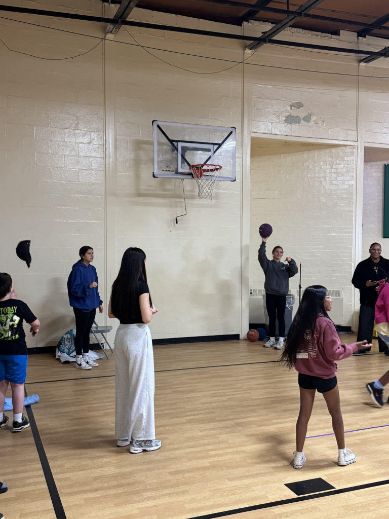 Tap students are helping elementary students in a basketball game.