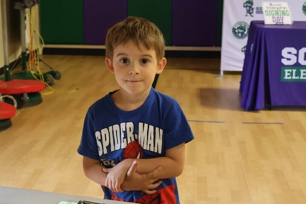 A boy is standing with his arms crossed.
