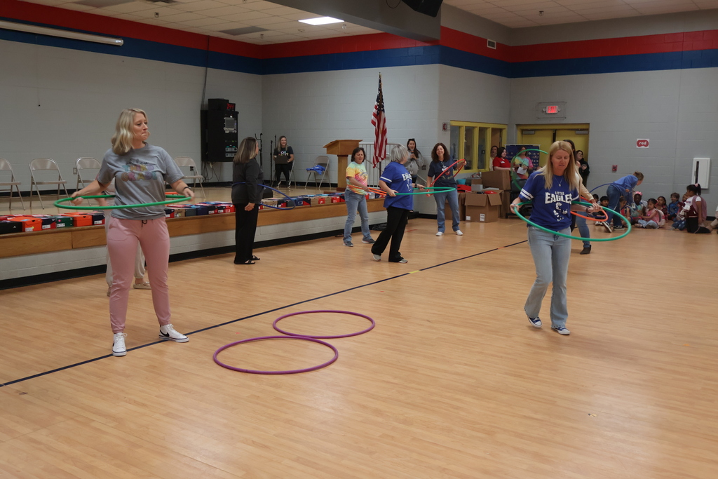 Teachers and the principal all have hula hoops to participate in an activity.