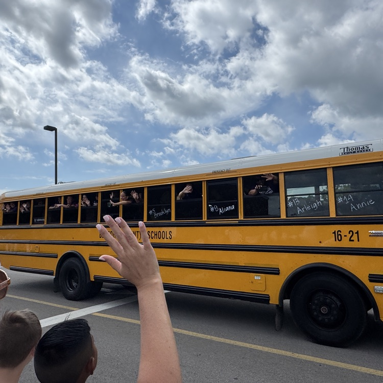 students waving from a bus