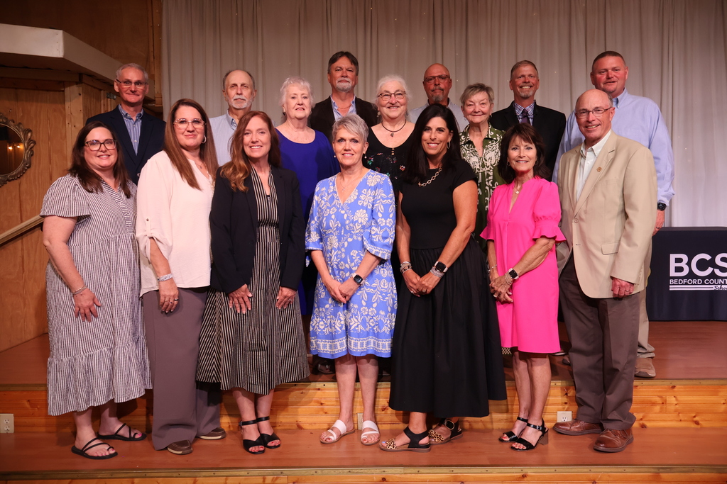 Retirees, along with the superintendent and school board members from Bedford County Schools pose for a group picture on the stage.