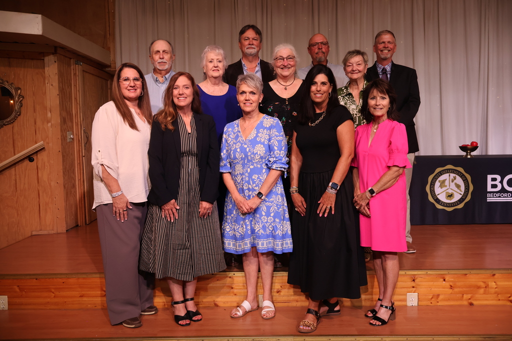 Retirees, along with the superintendent from Bedford County Schools pose for a group picture on the stage.