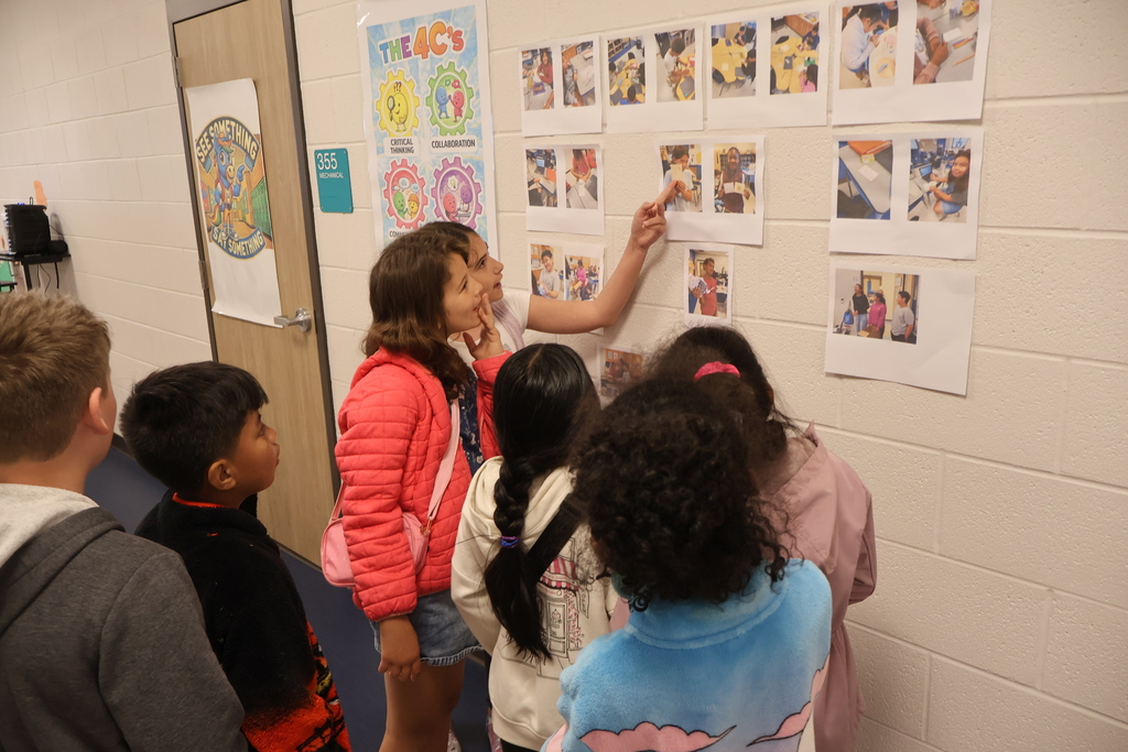 Several students are pointing at pictures on the wall.