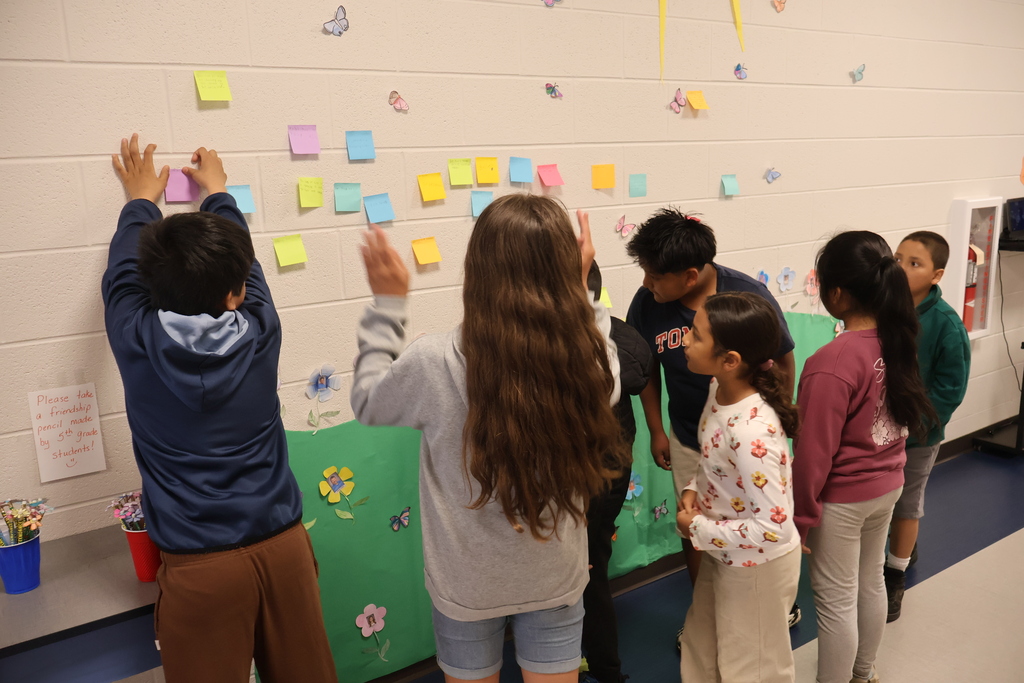 Students are putting sticky notes on the wall.