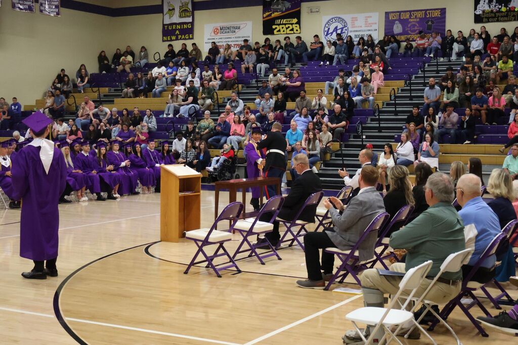 A student is shaking hands with a member of the military while be recognized for an award. 