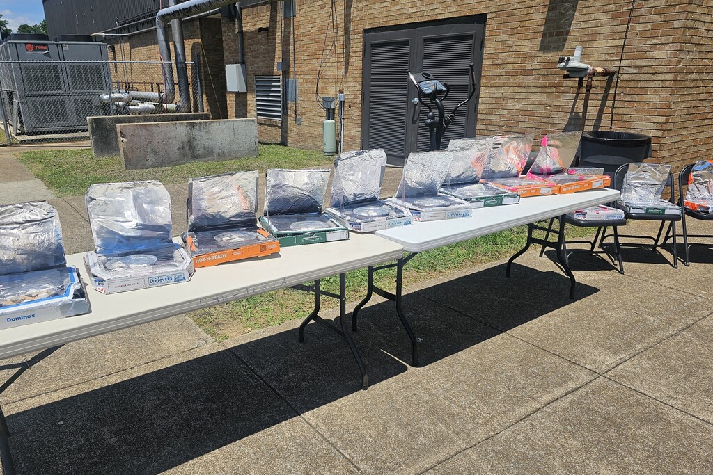 A table with nine pizza boxes that students turned into to solar ovens to make smores.
