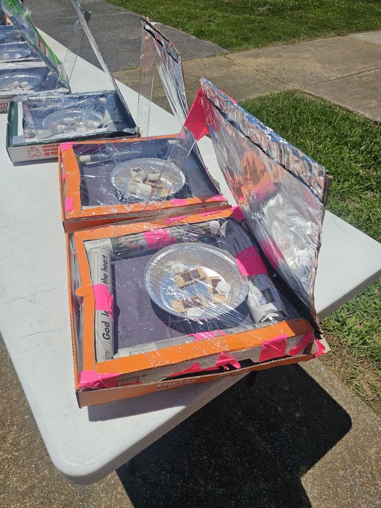 A table with five pizza boxes that students turned into to solar ovens to make smores.