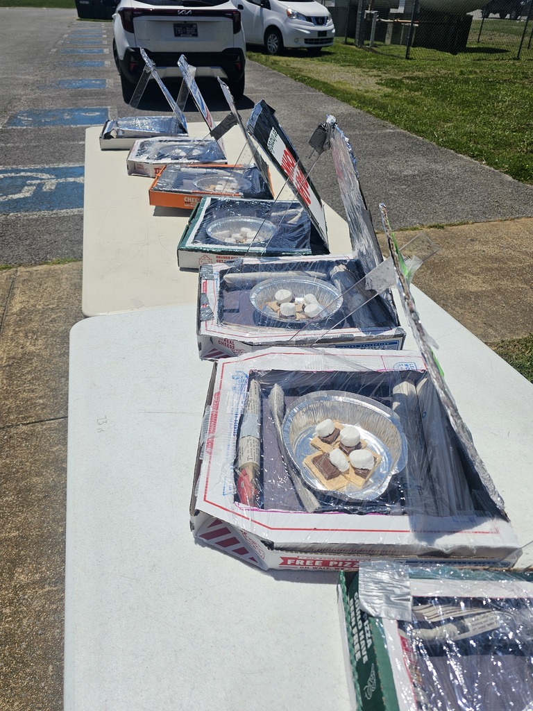 A table with seven pizza boxes that students turned into to solar ovens to make smores.