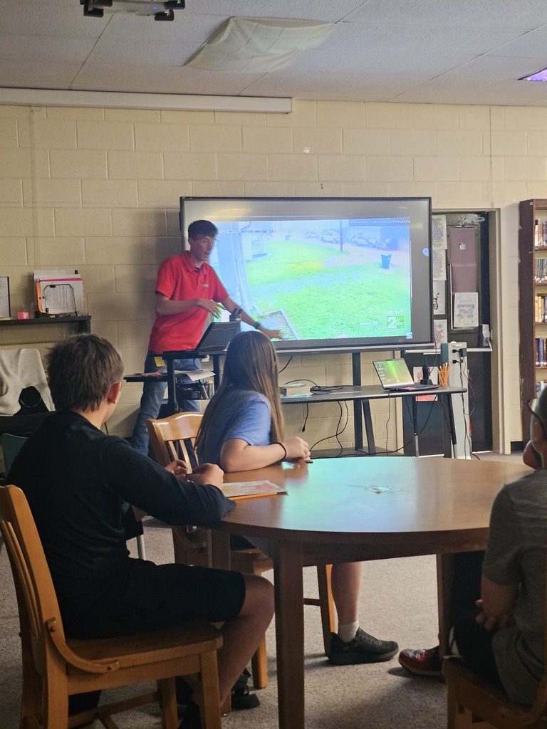 Meteorologist Elijah Kirby is giving a presentation to the class on a large screen.