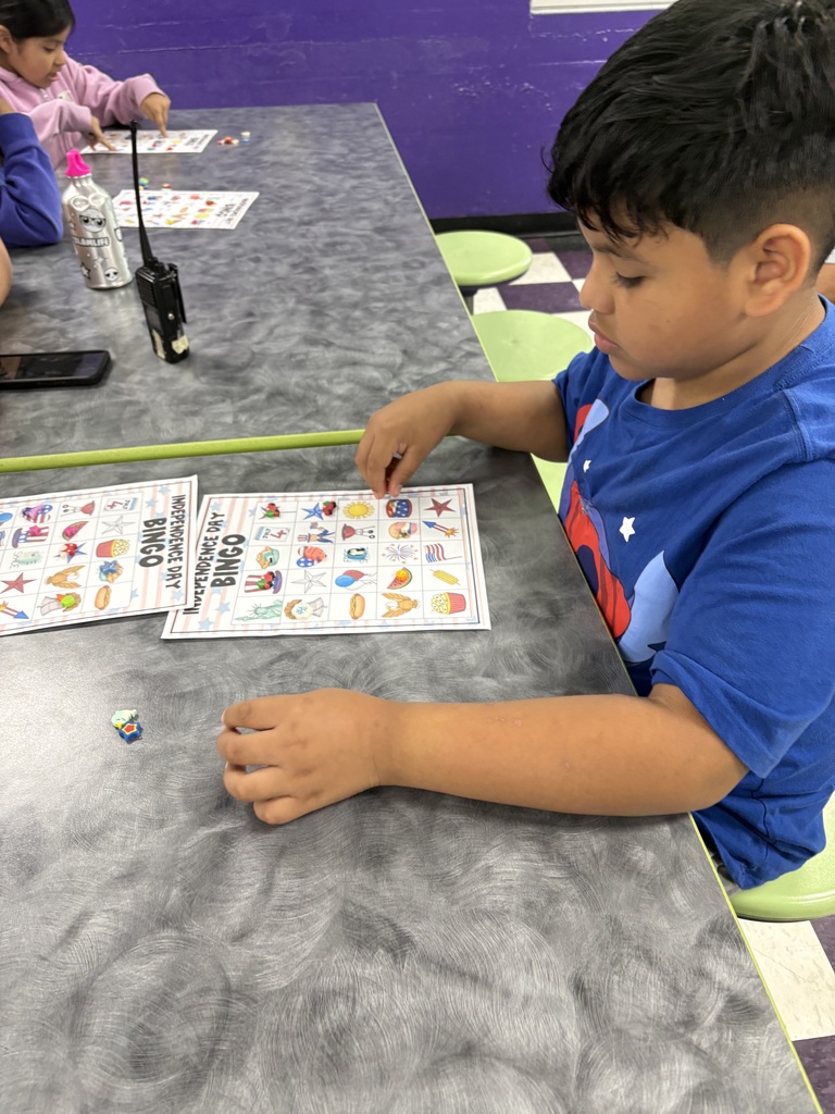 A student is sitting down at a table with their bingo sheet and the pieces that they will use to mark their sheets.