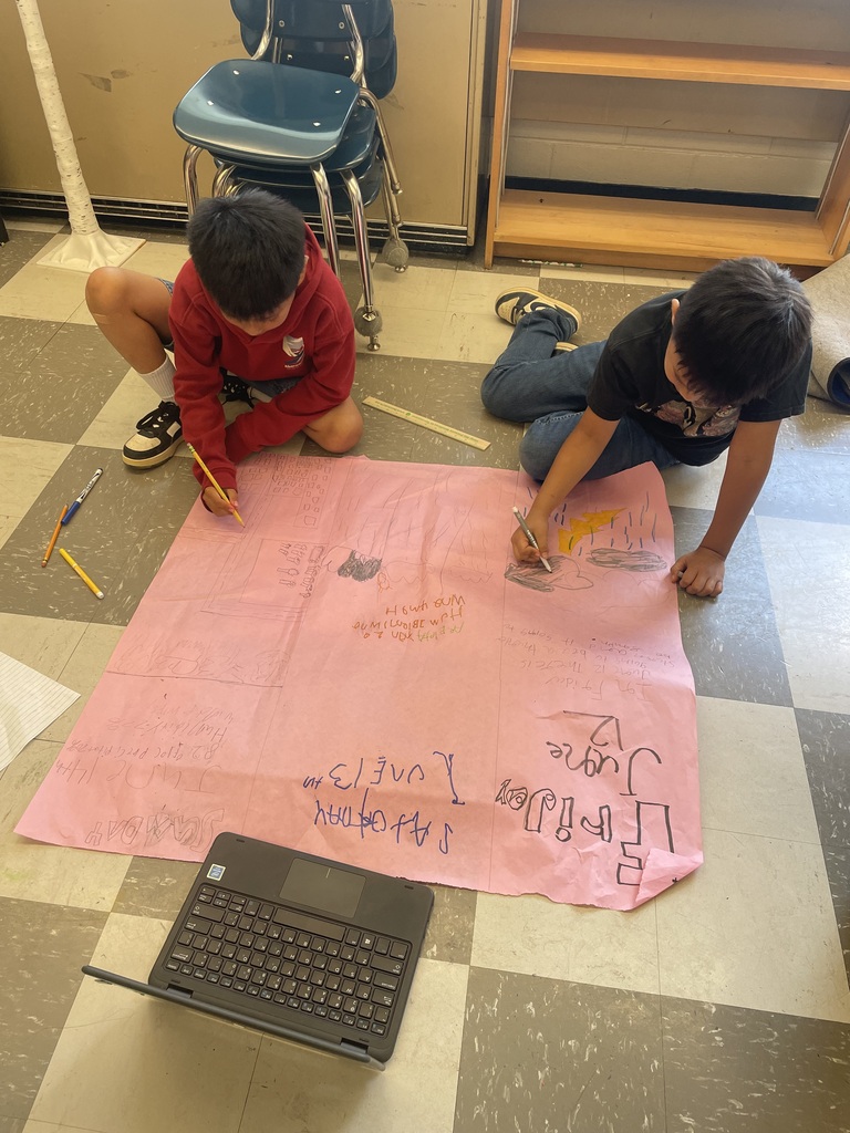 Students are on the floor coloring on a large piece of pink paper their predictions for this weekend's weather forecast.