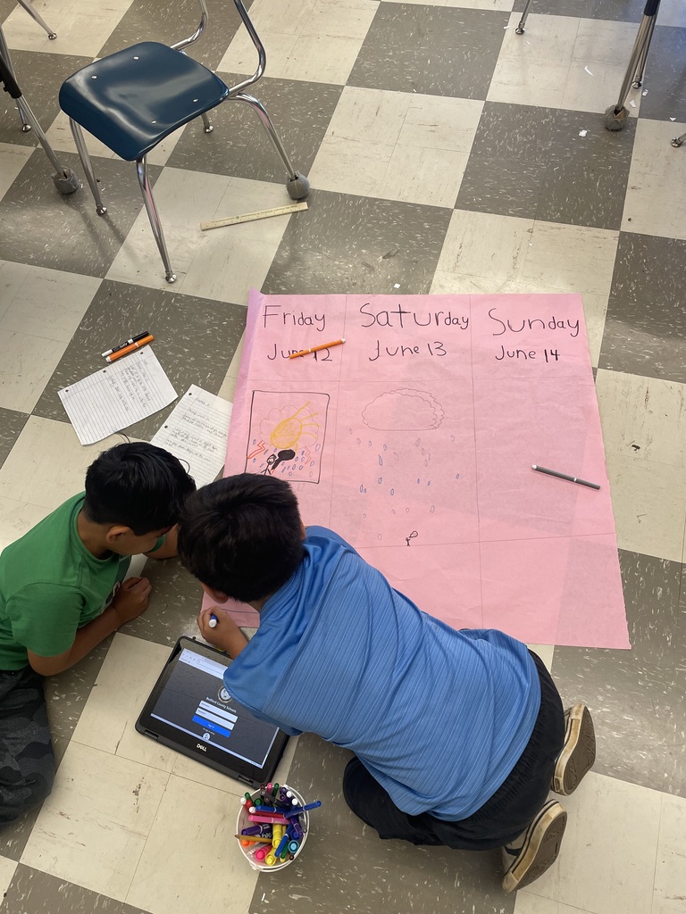 Students are on the floor coloring on a large piece of pink paper their predictions for this weekend's weather forecast.