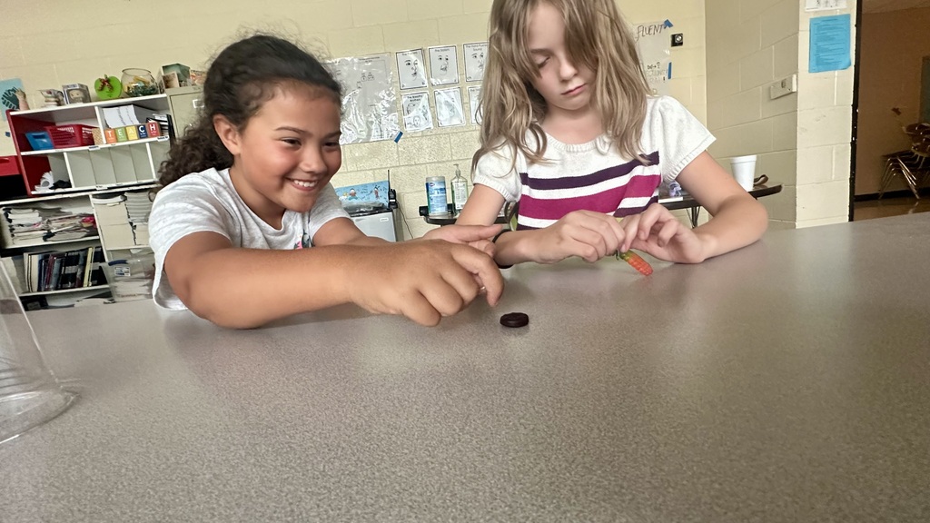 Two students are holding gummy worms and gummy lifesavers. 