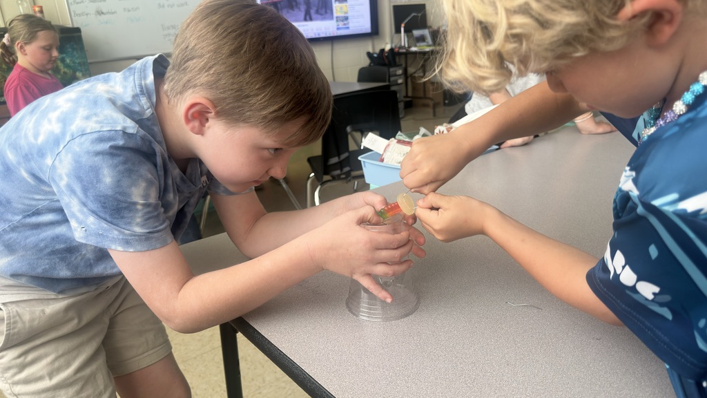 Two students are holding gummy worms and gummy lifesavers while participating in an activity. 