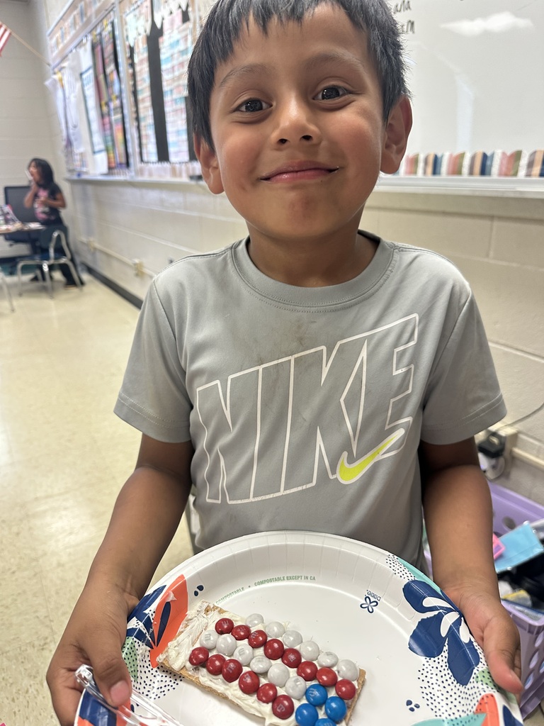 A student is holding a plate with a graham cracker he decorated to look like the American flag.