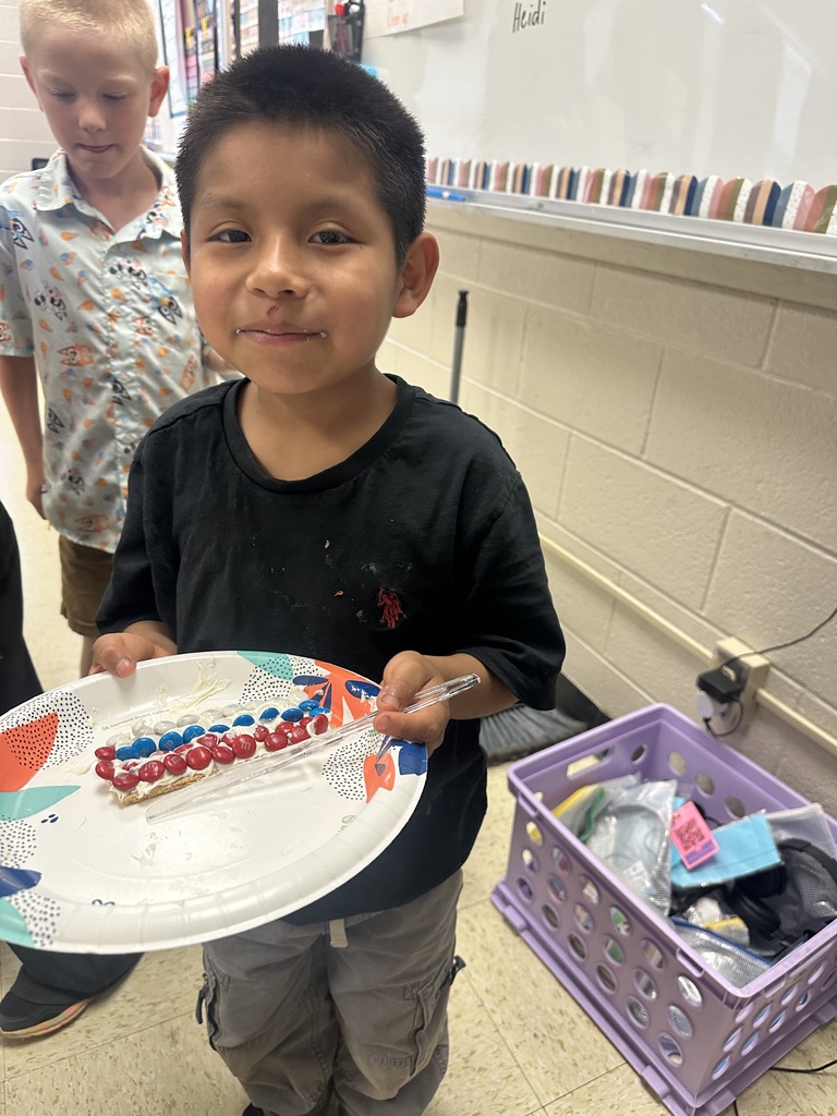 A student is holding a plate with a graham cracker he decorated to look like the American flag.