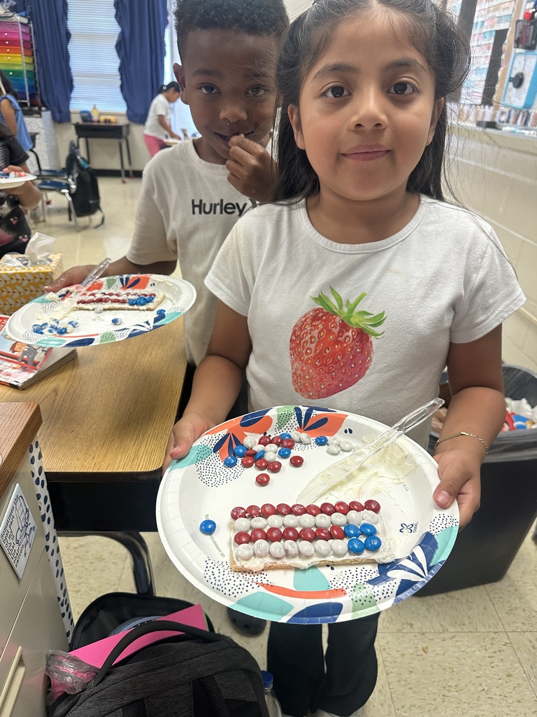 Two students are holding a plate with a graham cracker they decorated to look like the American flag.