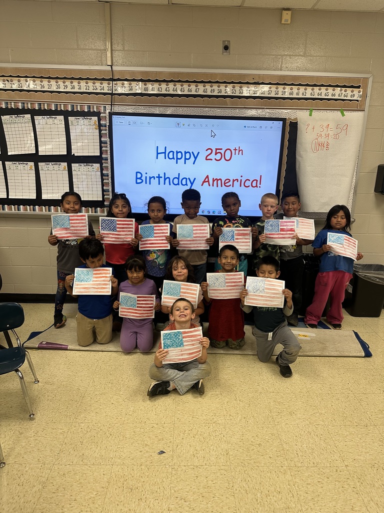 A group of students are posing for a group picture holding up a piece of paper that they decorated to look like the American flag.