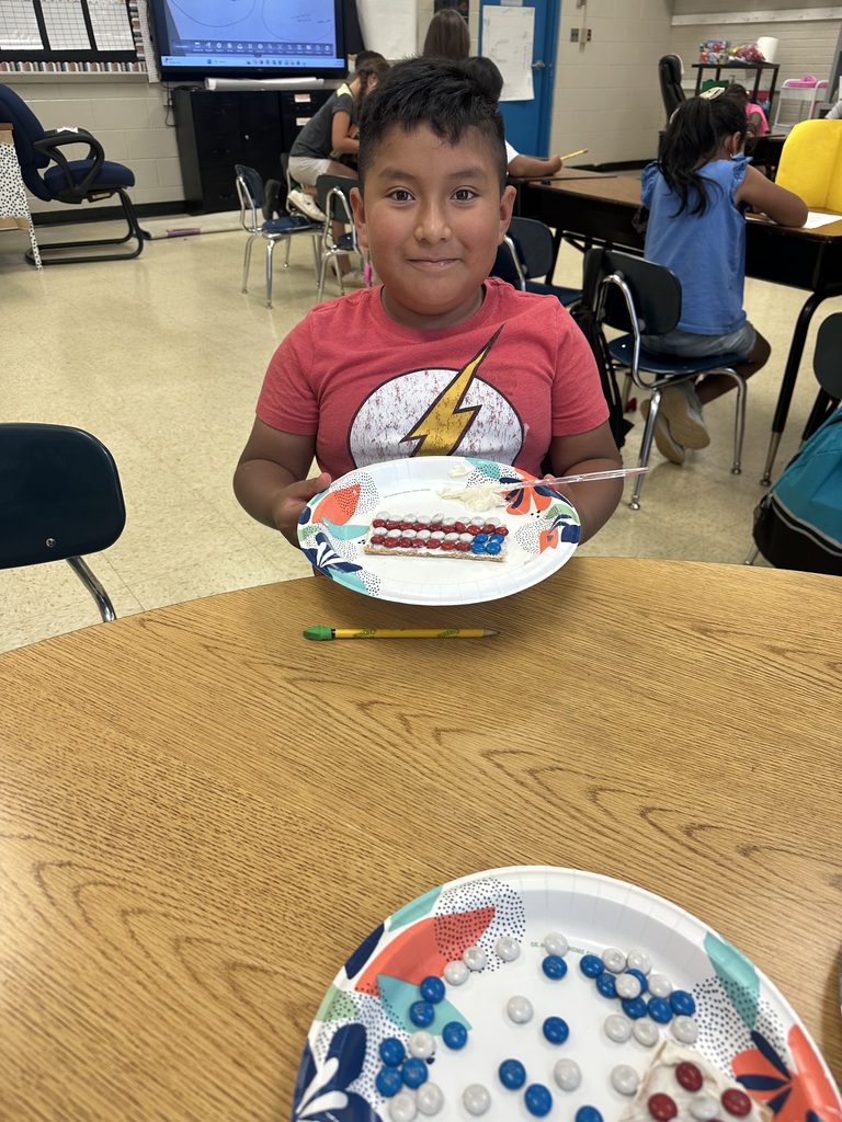 A student is holding a plate with a graham cracker he decorated to look like the American flag.