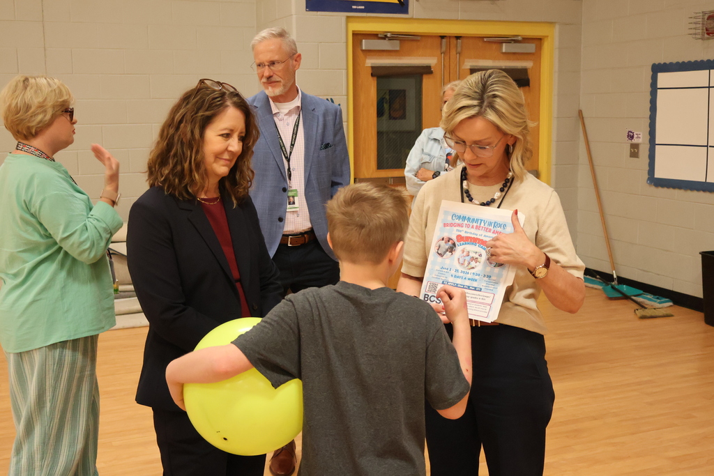 A student is pointing at a Summer Learning Camp flyer that is being held by a staff member. 