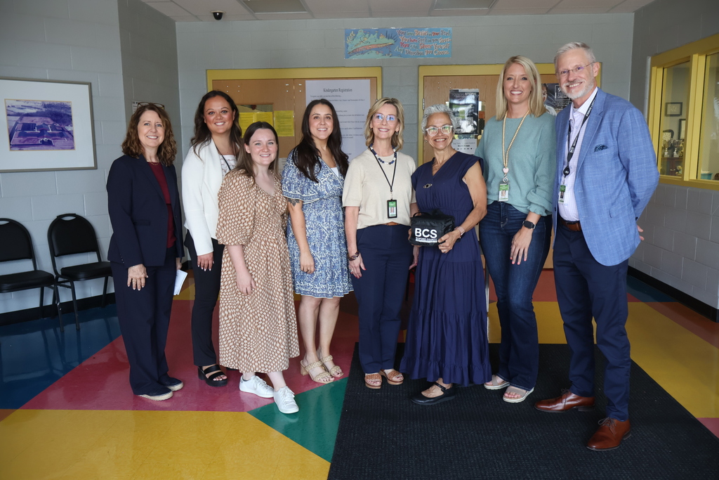 There are eight people posed for a group picture in the lobby of Learning Way Elementary School. 