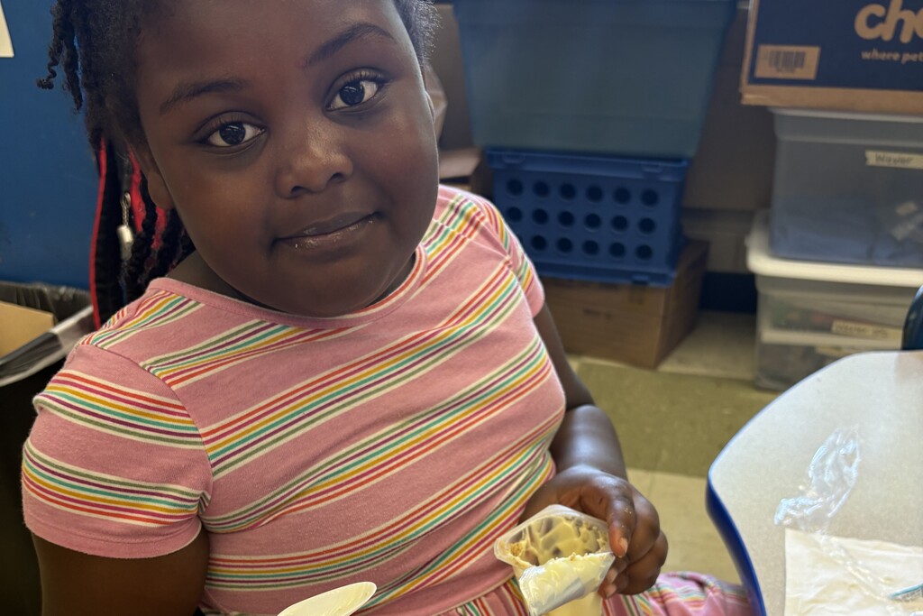 A student is seated in a chair holding up their snack that they are about to eat. 