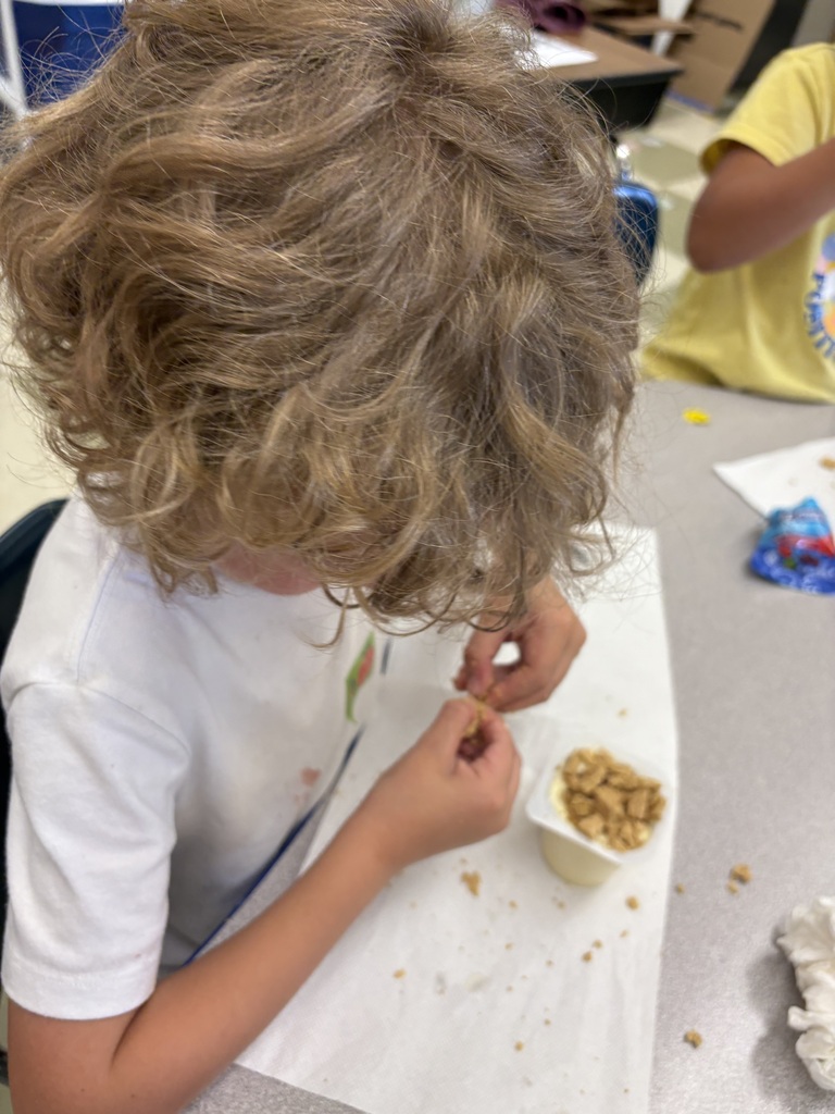 A student is seated at a table making their snack that they are about to eat.