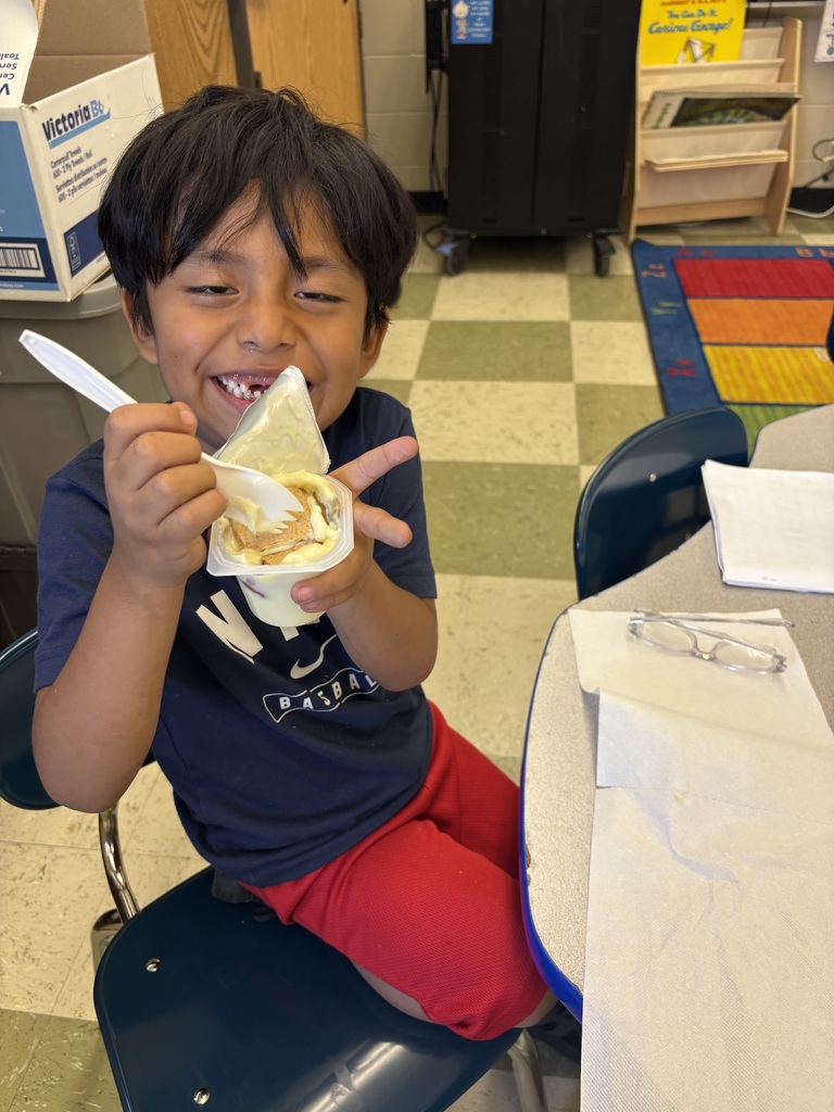 A student is seated in a chair holding up their snack that they are about to eat. 
