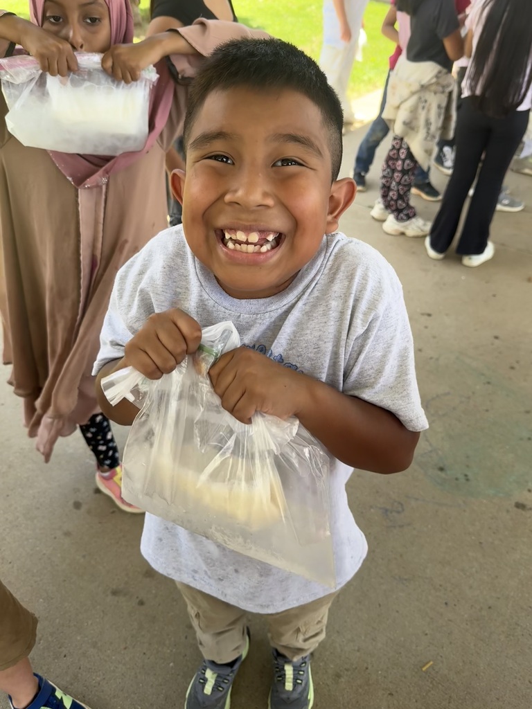 A student is holding a clear sandwich bag that contains ice cream that they made from milk.