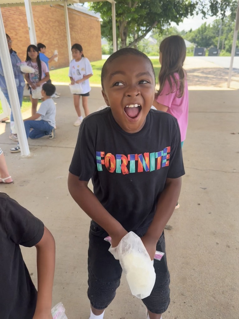 A student is holding a clear sandwich bag that contains ice cream that they made from milk.
