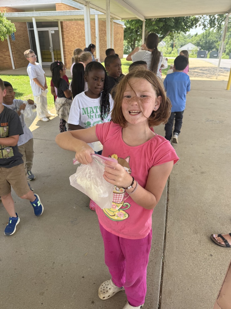 A student is holding a clear sandwich bag that contains ice cream that they made from milk.