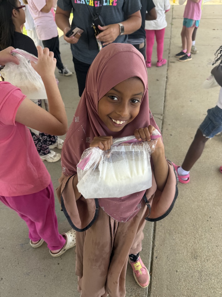 A student is holding a clear sandwich bag that contains ice cream that they made from milk.