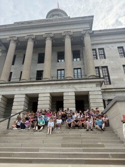 Students are sitting in steps in front of a building.