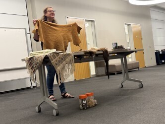 A speaker is standing in a room holding up artifacts from Tennessee history.