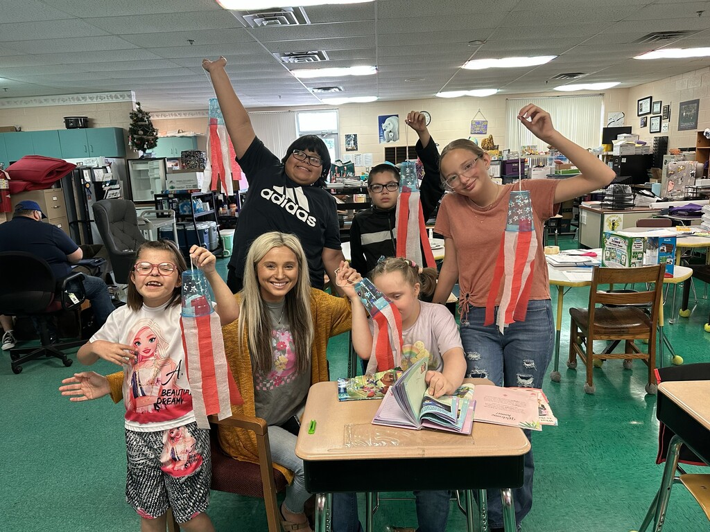 Students are posed for a picture in their classroom holding a flag windsock they created