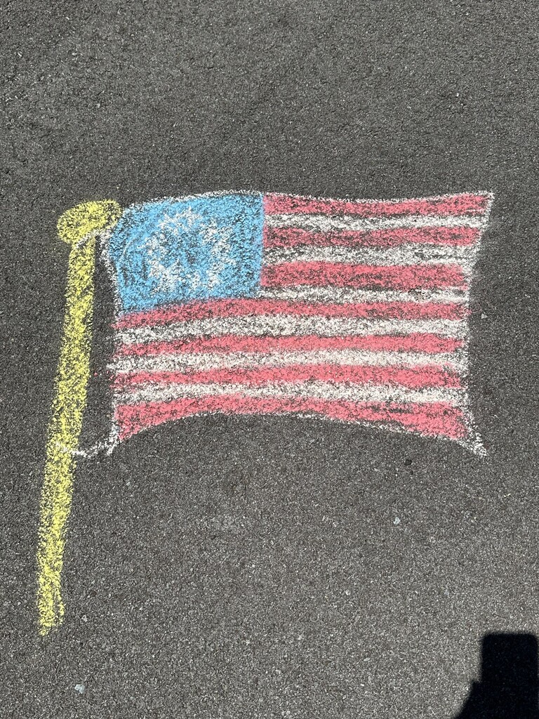A picture of the American flag on pavement that was drawn with chalk.