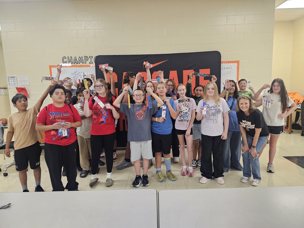 Students are posed for a group picture holding up the bookmarks they designed.