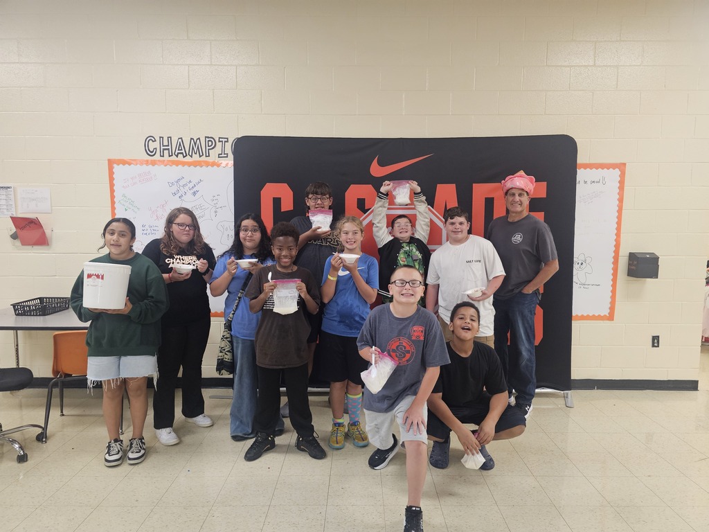 Students are posed for a group picture as they hold the ice cream that they made.