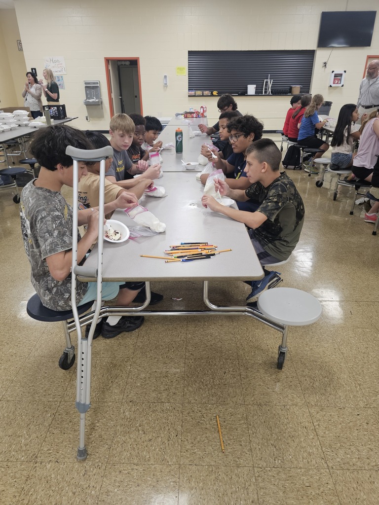 Students are seated at cafeteria tables as they work on their bags to make ice cream.