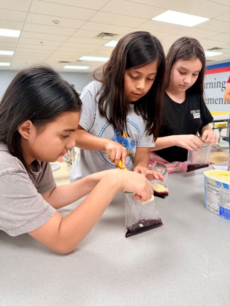 Three students are putting ice cream into bags.