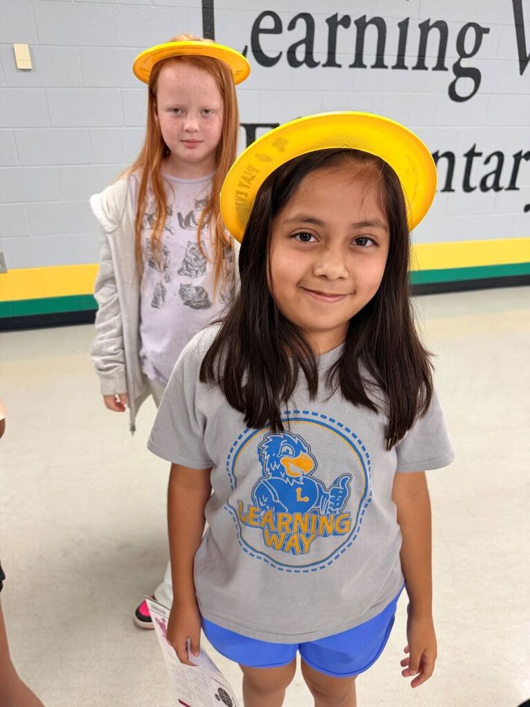 Two students are standing up wearing hats.