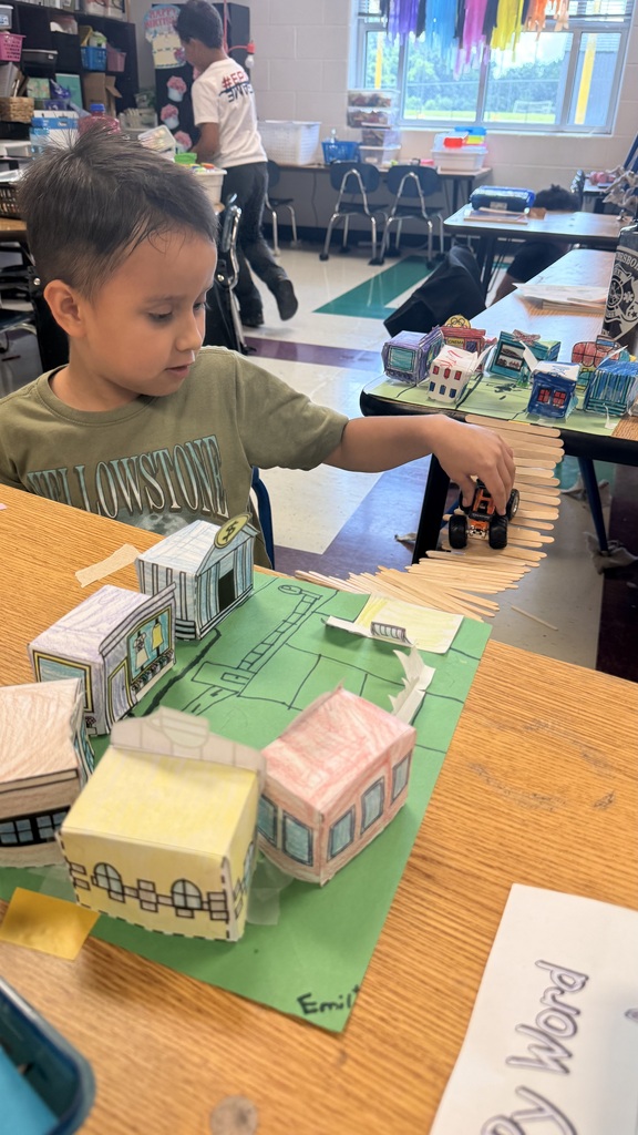 A student is standing beside the table testing out his bridge with a toy car.