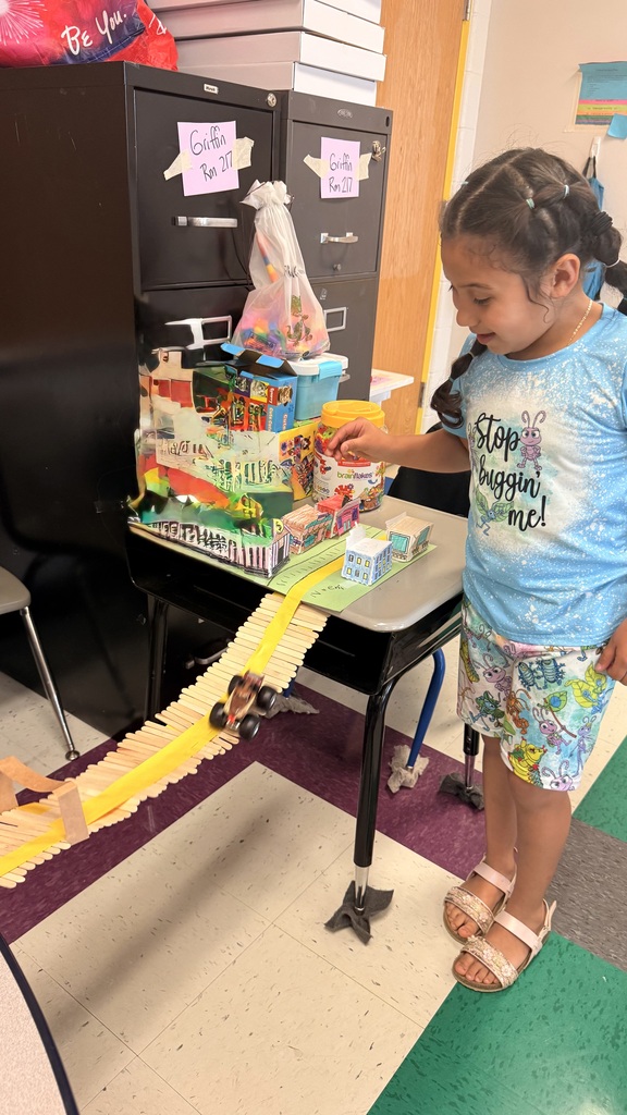 A student is standing beside the table testing out her bridge with a toy car.