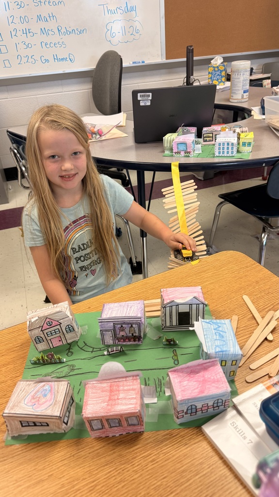 A student is standing beside the table testing out her bridge with a toy car.