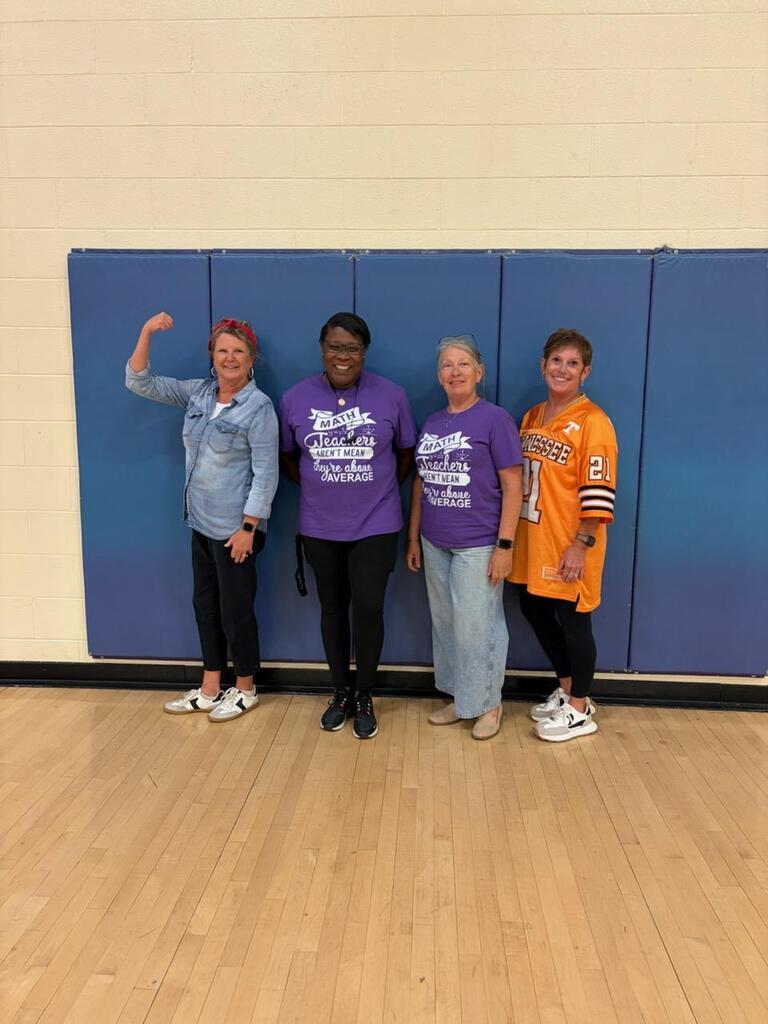 Four teachers are standing in the gym smiling for a group picture.