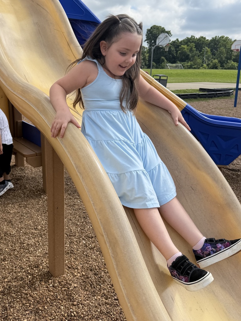 A female student is sliding down a slide.